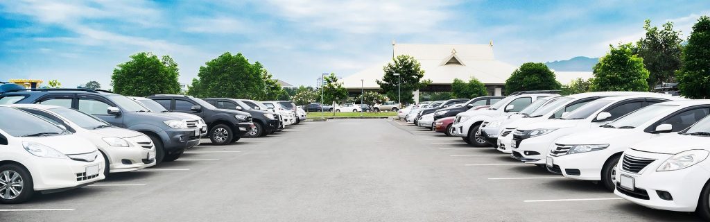 Rows of vehicles parked in a large outdoor parking lot.