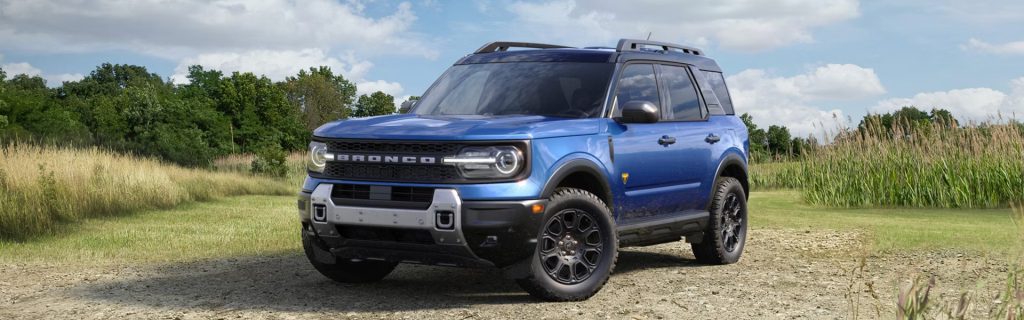 Blue Ford Bronco Sport parked on a dirt path in a grassy field