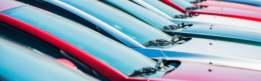row of colorful cars lined up at a dealership lot